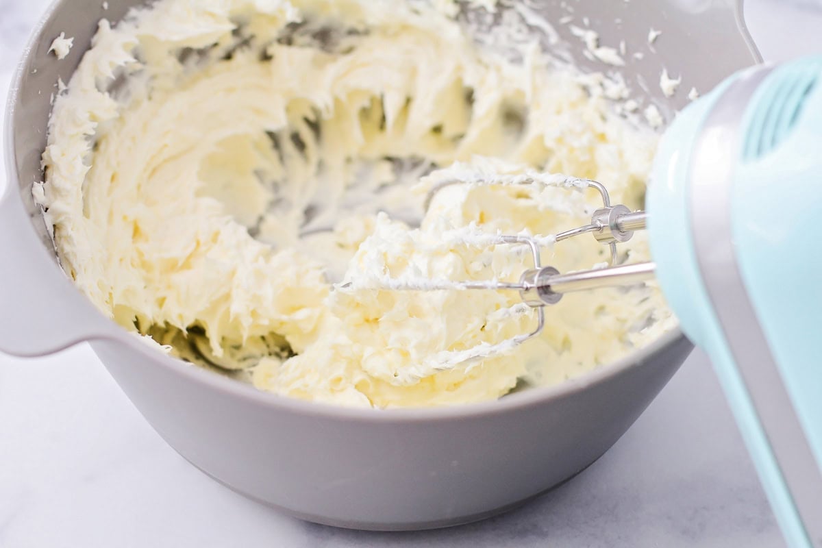 Mixing cream cheese, butter, egg and vanilla together in mixing bowl.