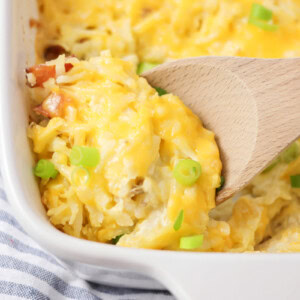 Cheesy hashbrown casserole baked in baking dish with scoop being spooned out.
