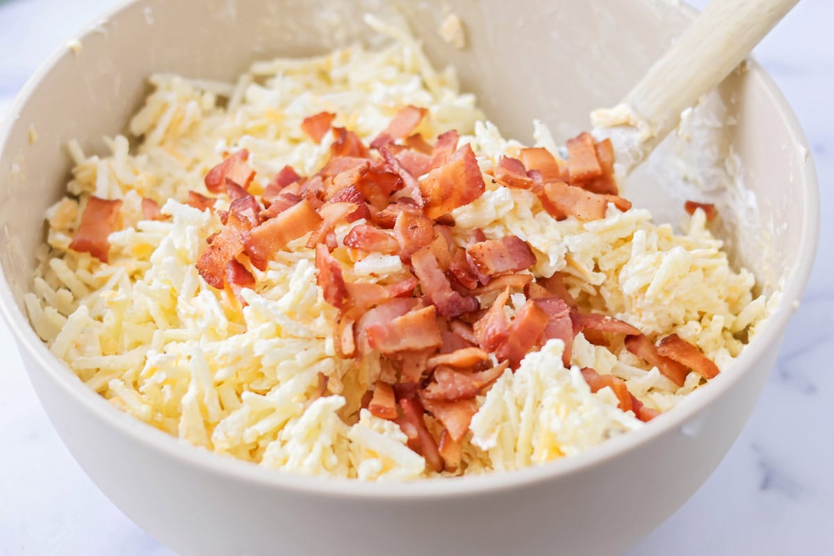 Cheesy Hashbrown Casserole recipe ingredients being mixed in bowl.
