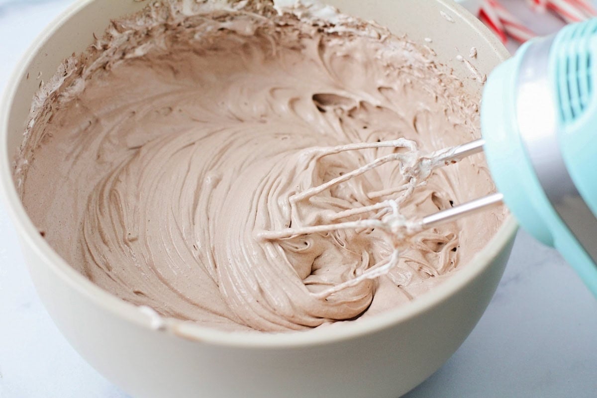 Whipping cool whip, marshmallow cream, and hot chocolate in a bowl.