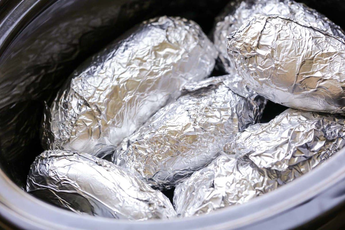 Baked potatoes wrapped in aluminum foil in a crock pot