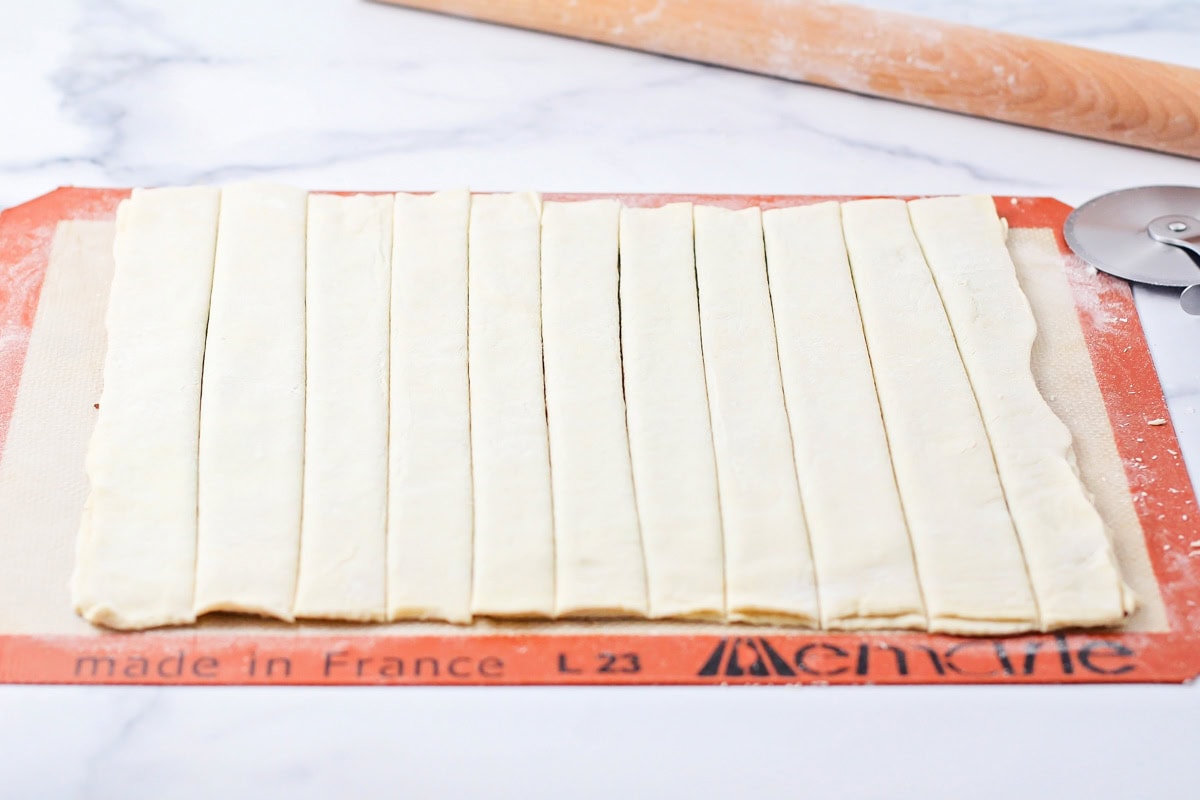 Cutting puff pastry into strips.