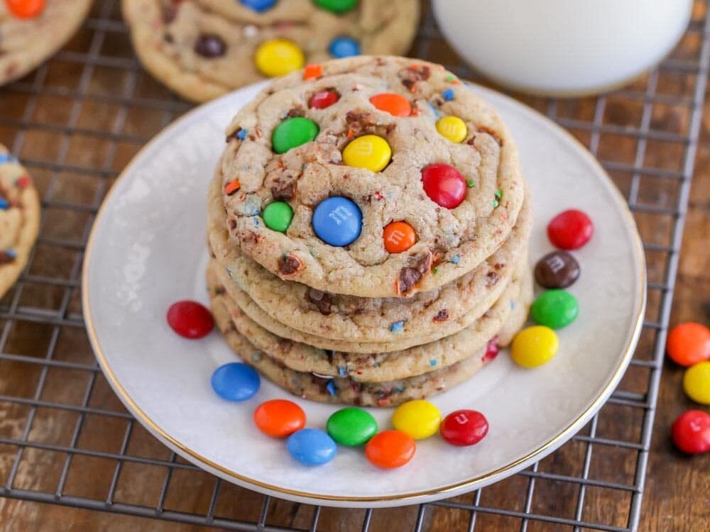 A stack of M&M cookie on a white plate.