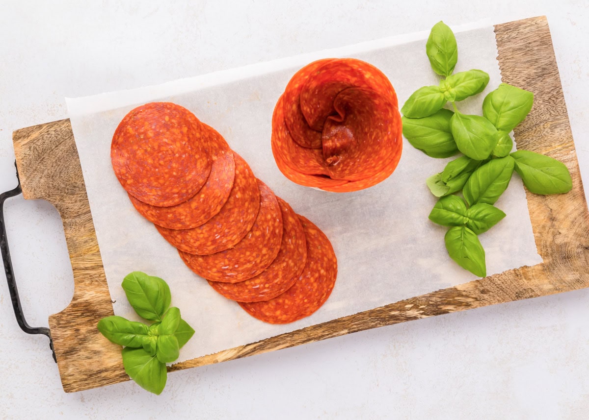 Pushing pepperoni into the glass jar.