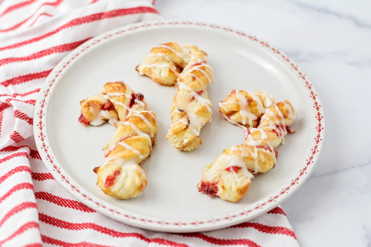 Three puff pastry candy canes on a plate.