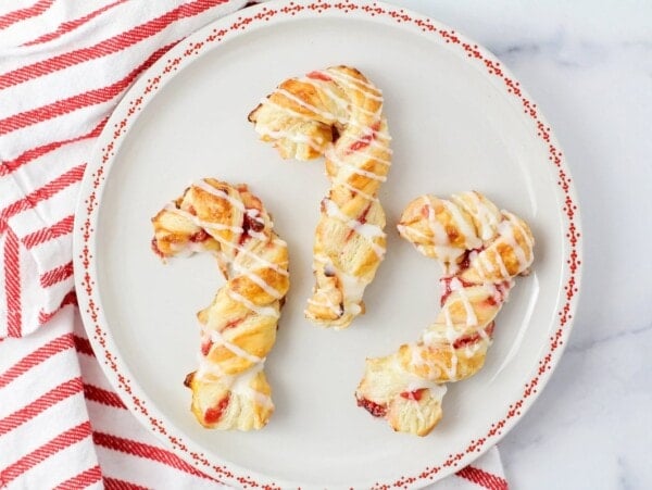 Puff pastry candy canes on a red and white plate.