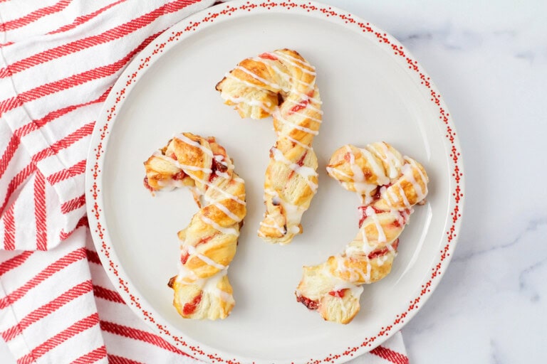 Puff pastry candy canes on a red and white plate.