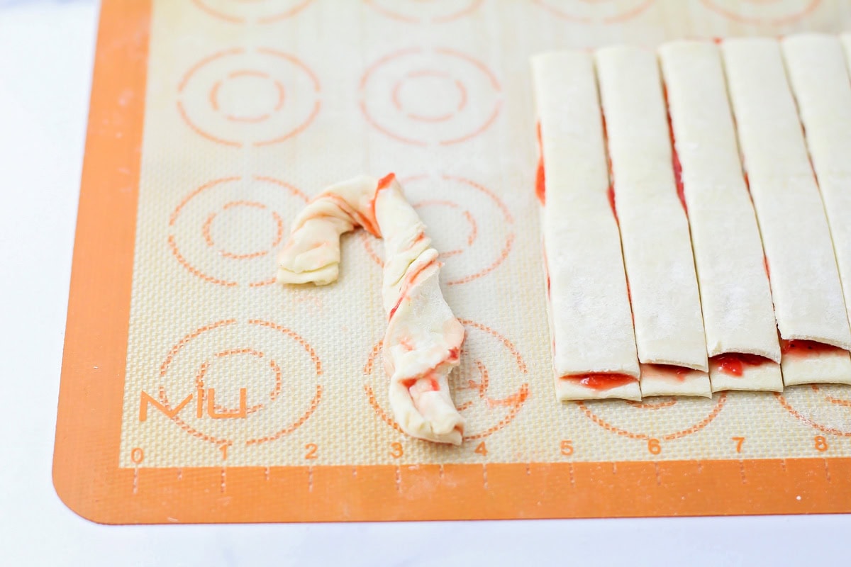 Twisting the puff pastry strips into candy cane shapes.