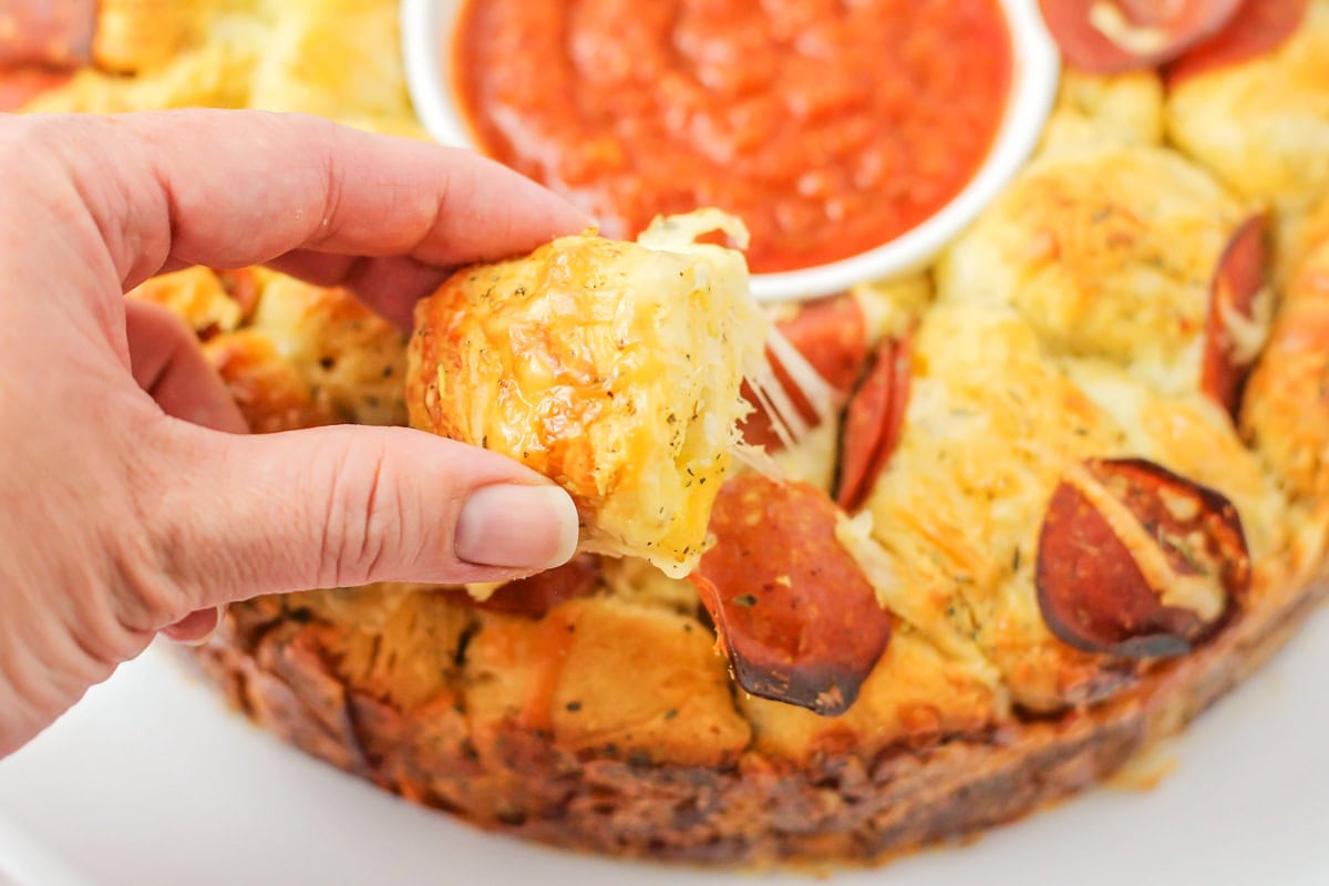 Pulling a piece from the pull apart pizza bread.