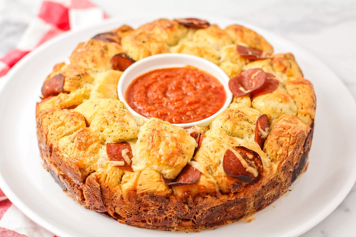 Pull apart pizza bread with a cup of pizza sauce in the center.