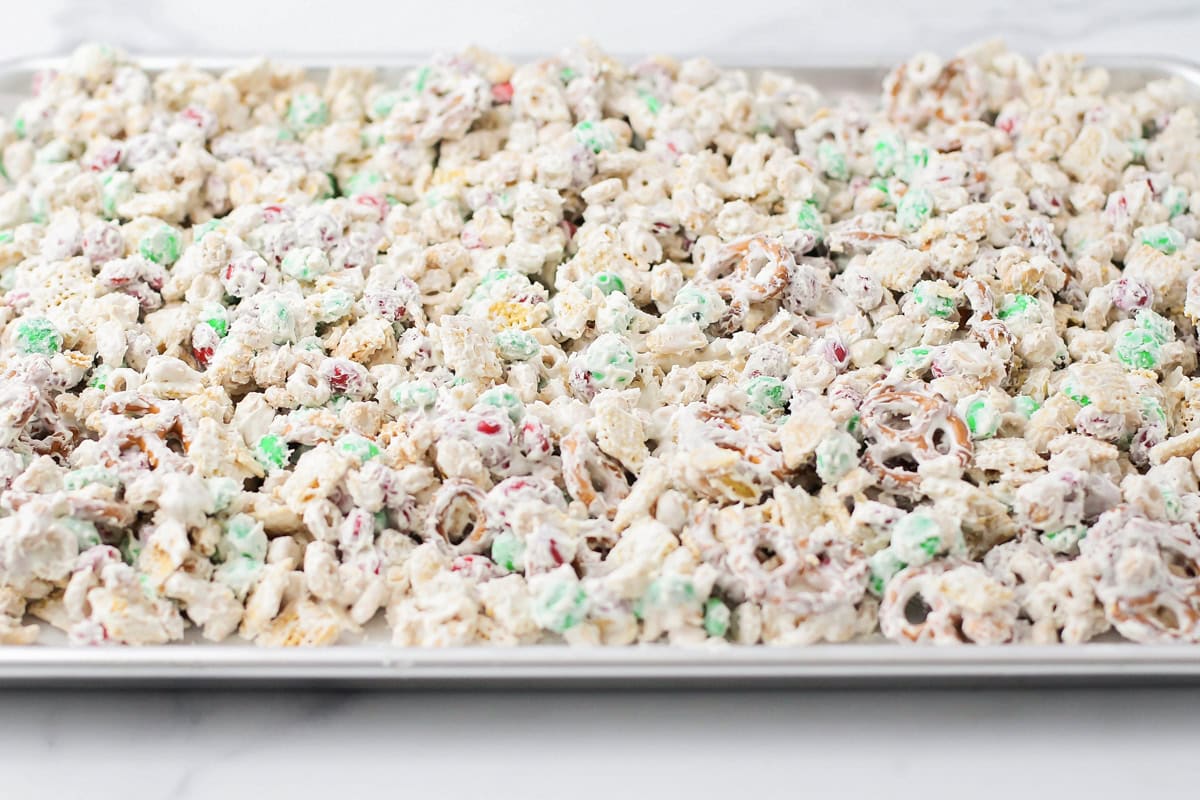 Spreading the snack mix on a cookie sheet to cool.