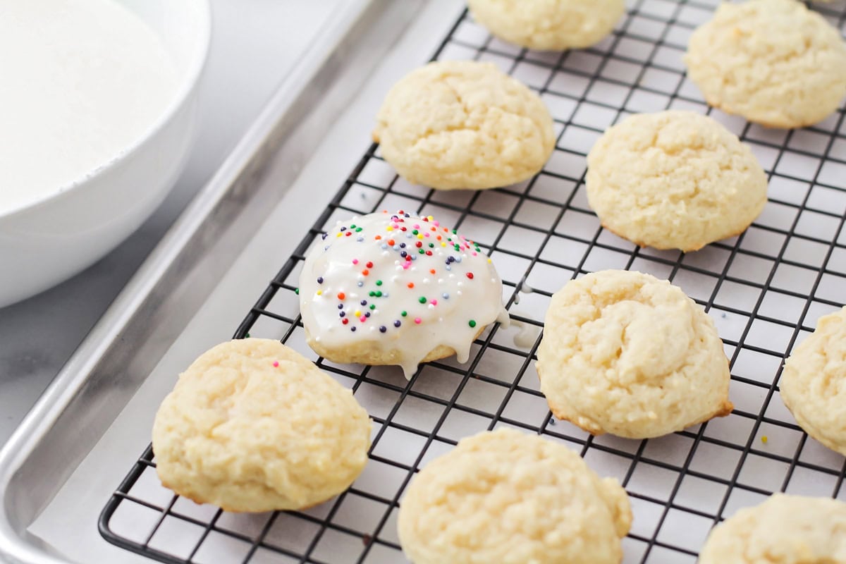 Frosting cookies with almond frosting and topping with colorful sprinkles.