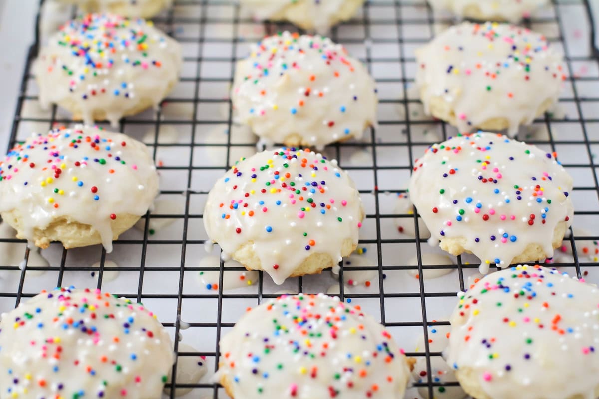 A wire rack topped with frosted ricotta cookies.