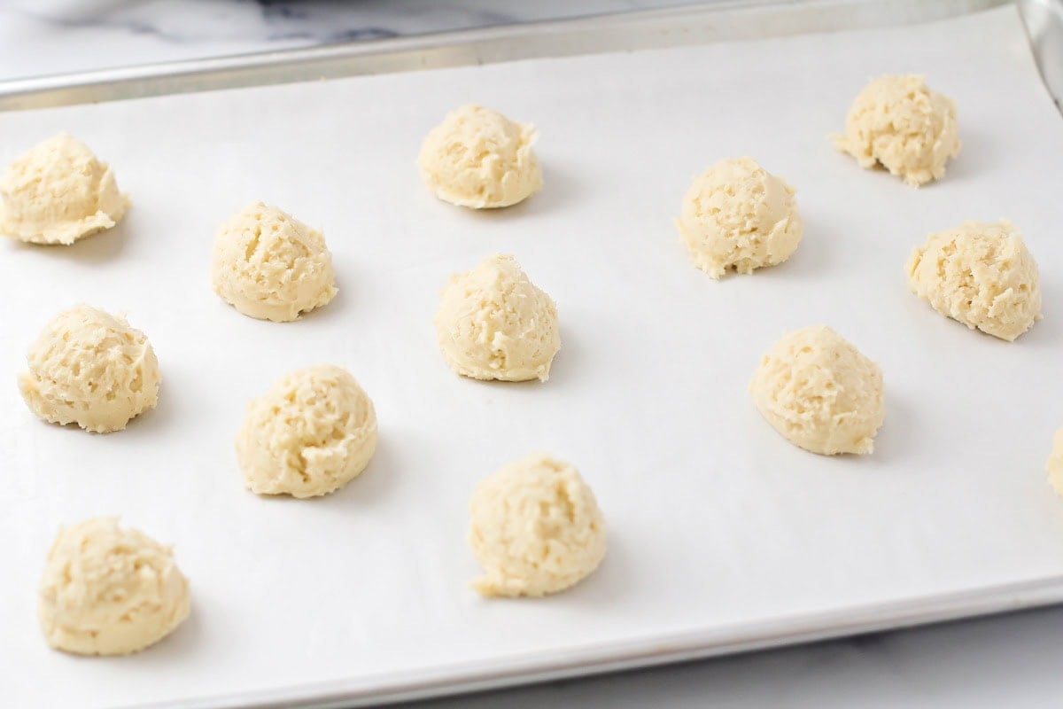 Cookie dough balls dropped on a lined baking sheet.