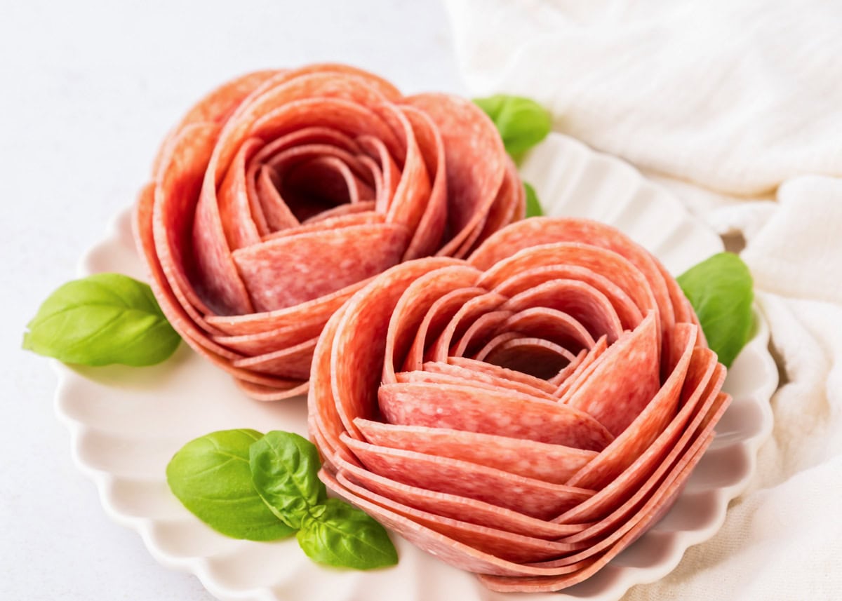 Two salami roses on a white plate.