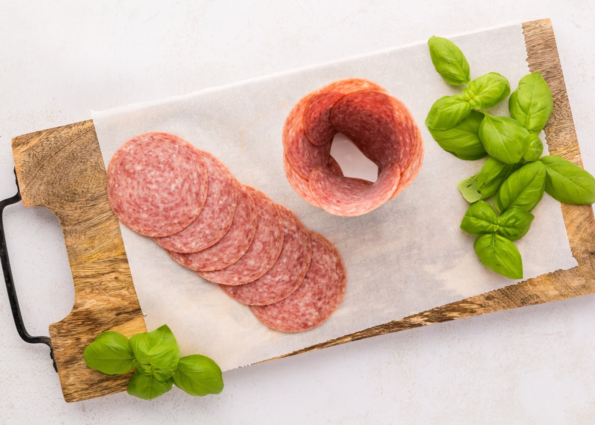 Placing layered salami around a glass jar.