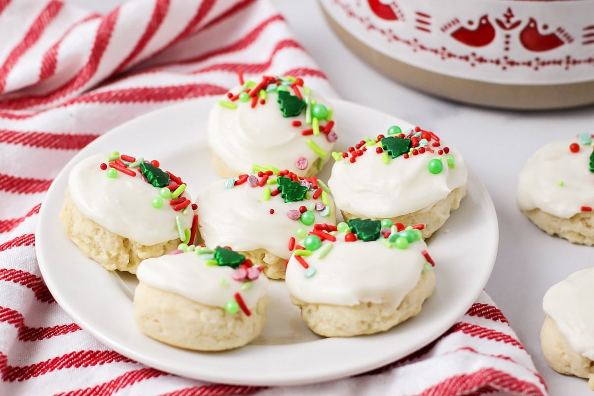 Several frosted santa cookies on a white plate.