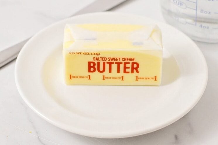 A stick of butter on a white plate.