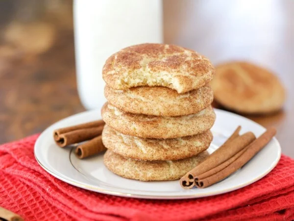 Snickerdoodle cookies stacked on each other on white plate.