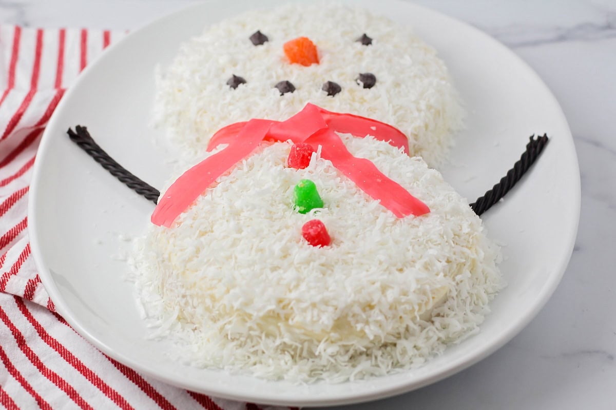 Adding chocolate chips and candy decorations to the snowman cake.