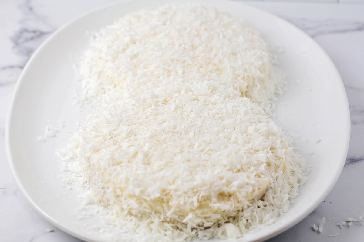 Topping frosted cakes with coconut flakes.