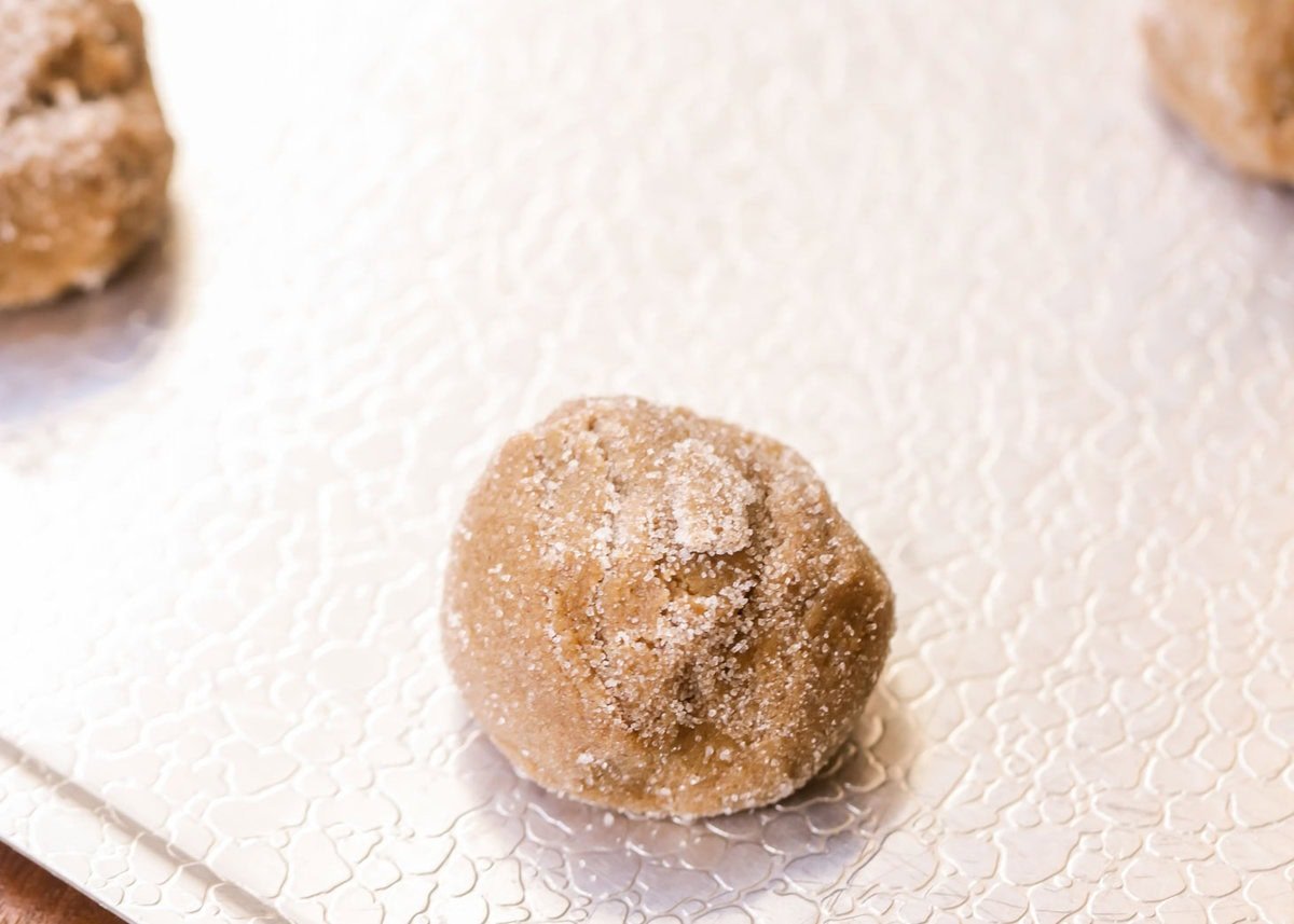 Balls of soft ginger cookie dough on cookie sheet.