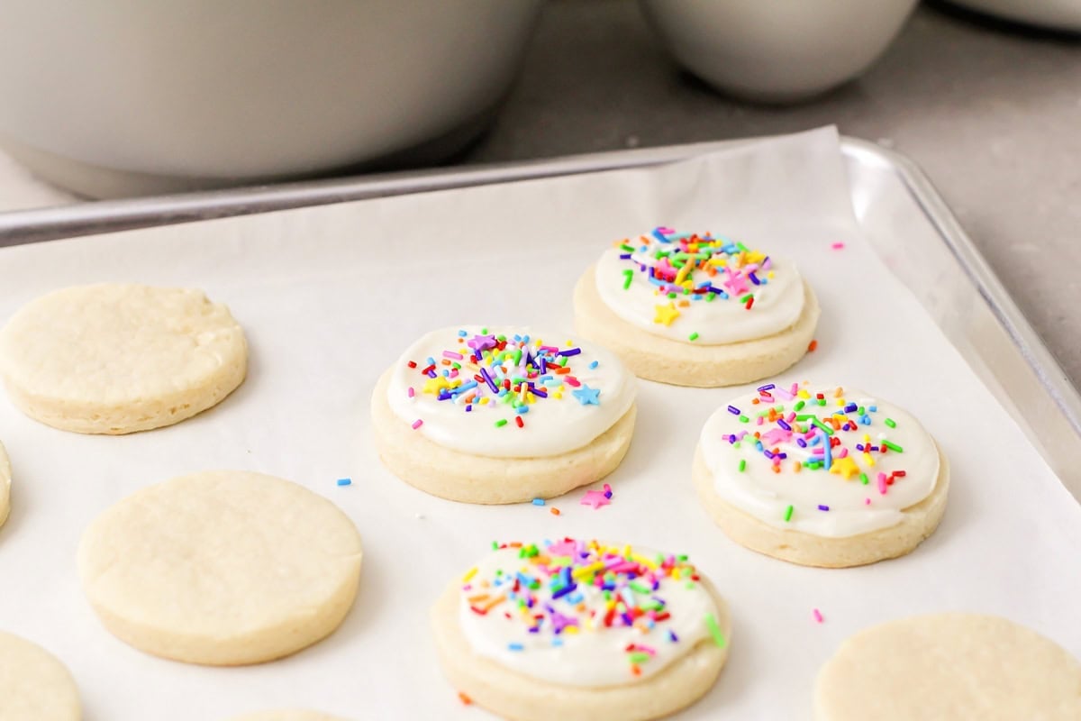 Topping baked cookies with sugar cookie frosting.