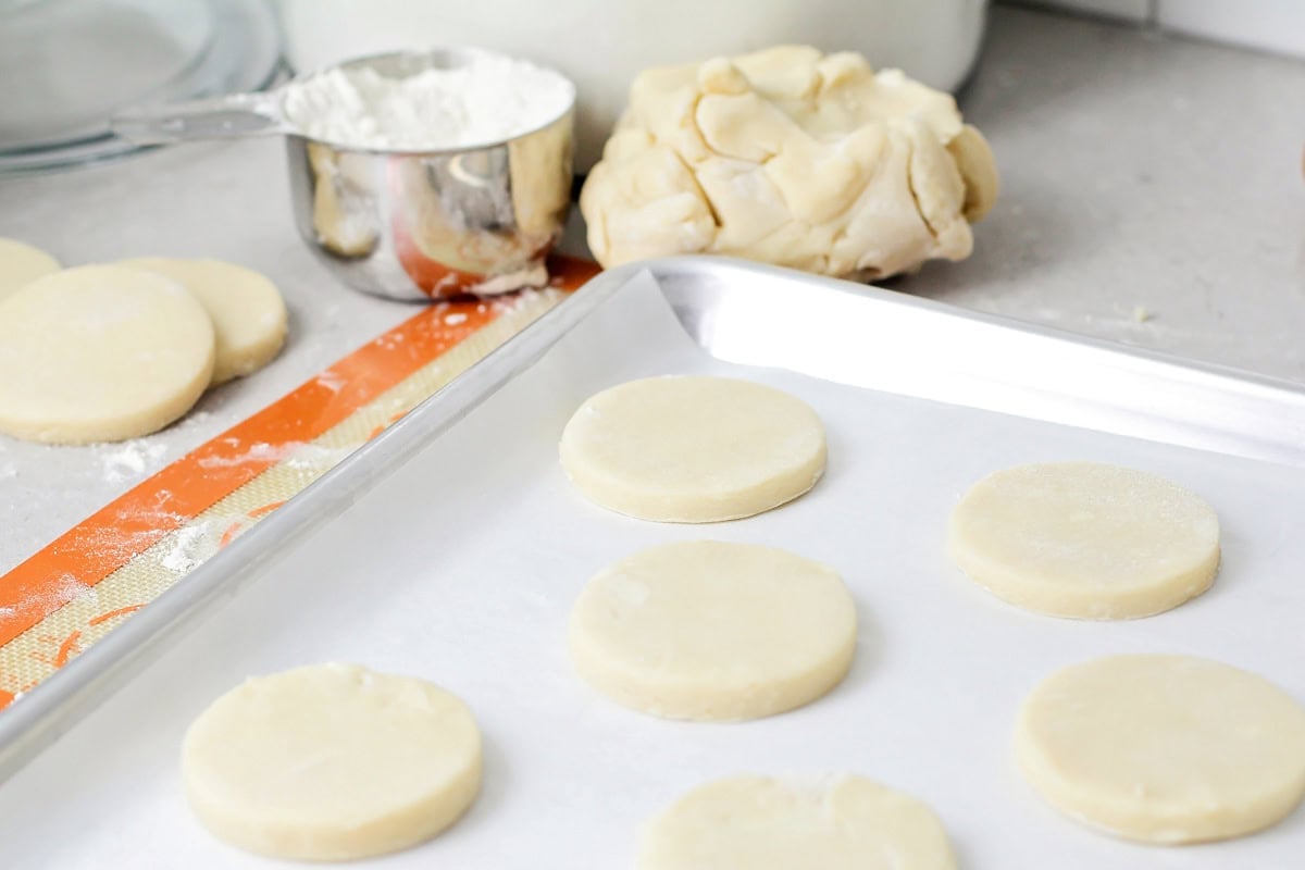 Sugar cookie dough rounds on cookie sheet with parchment paper.