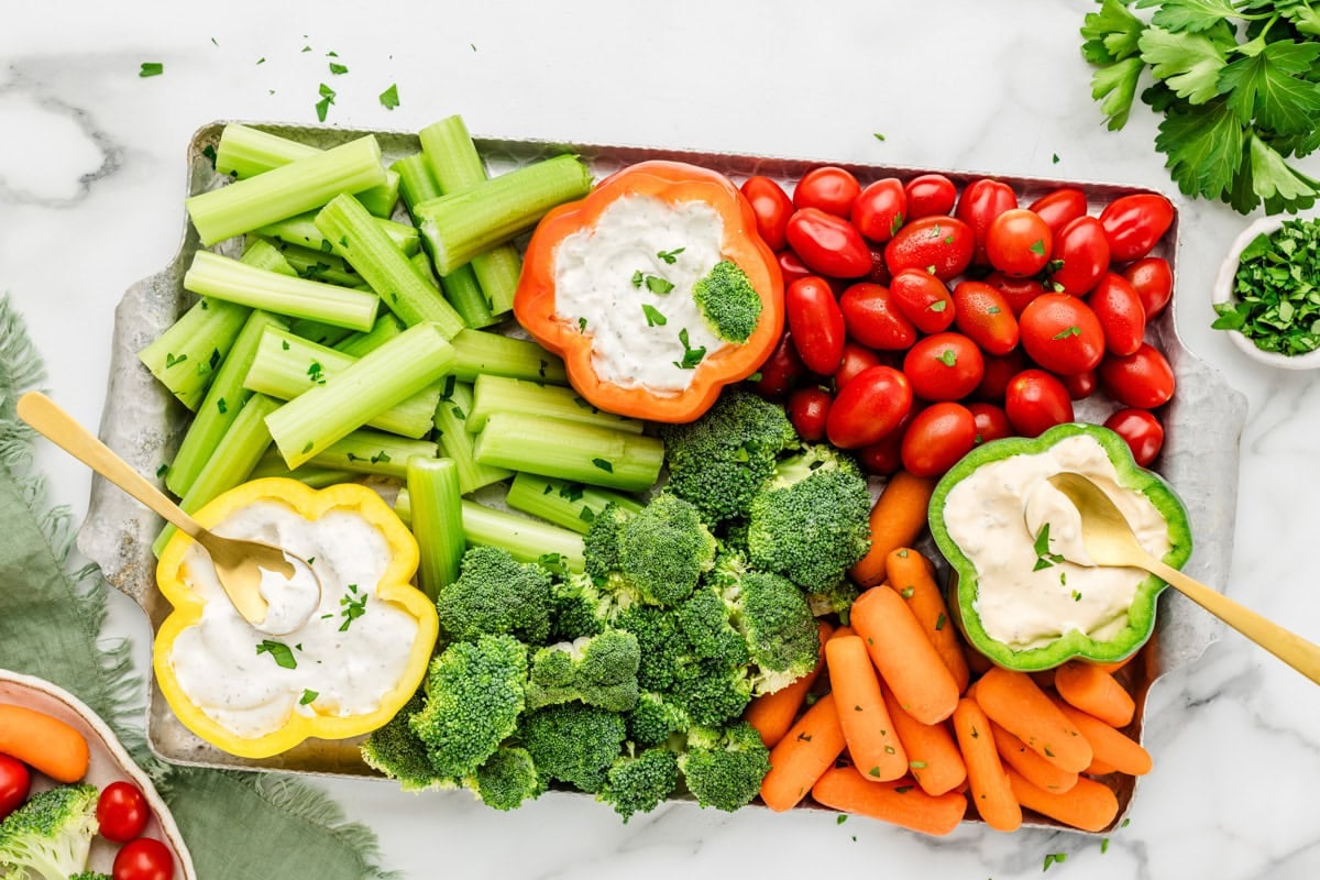 A veggie tray put together with veggies and dips served in bell peppers.