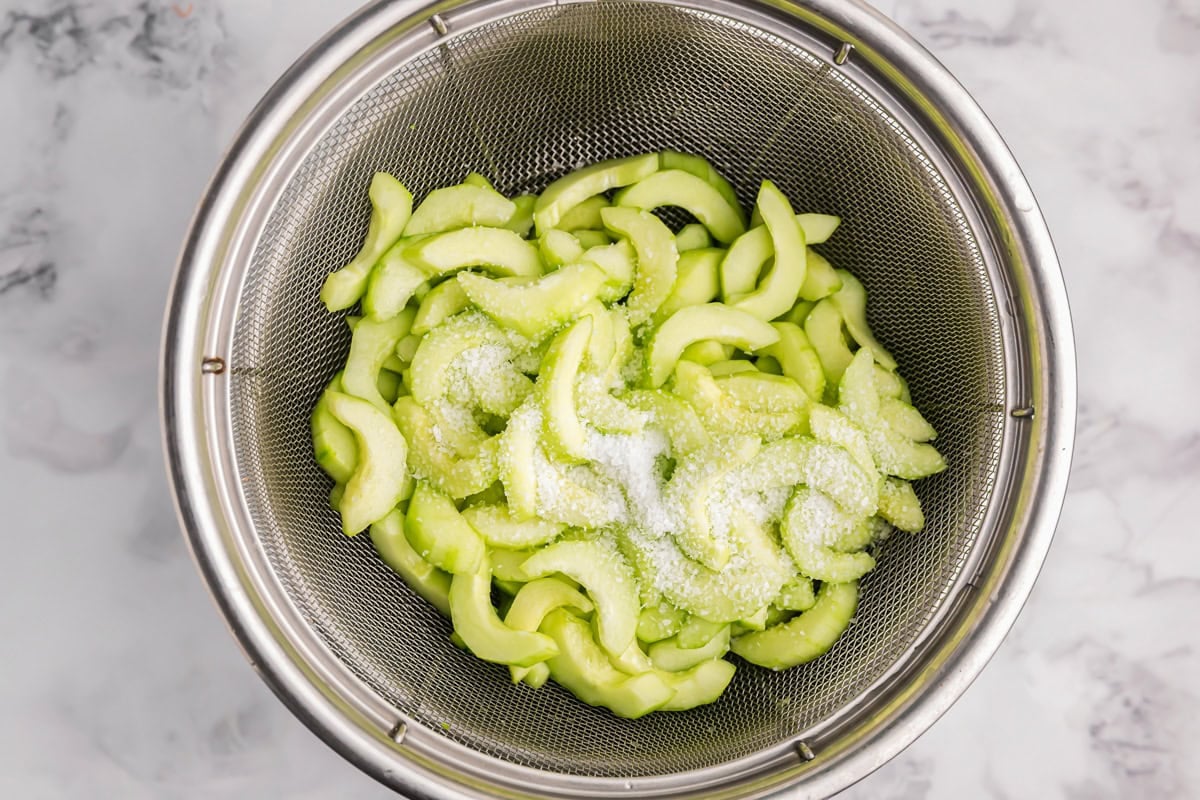 Salt on cucumbers in a strainer.