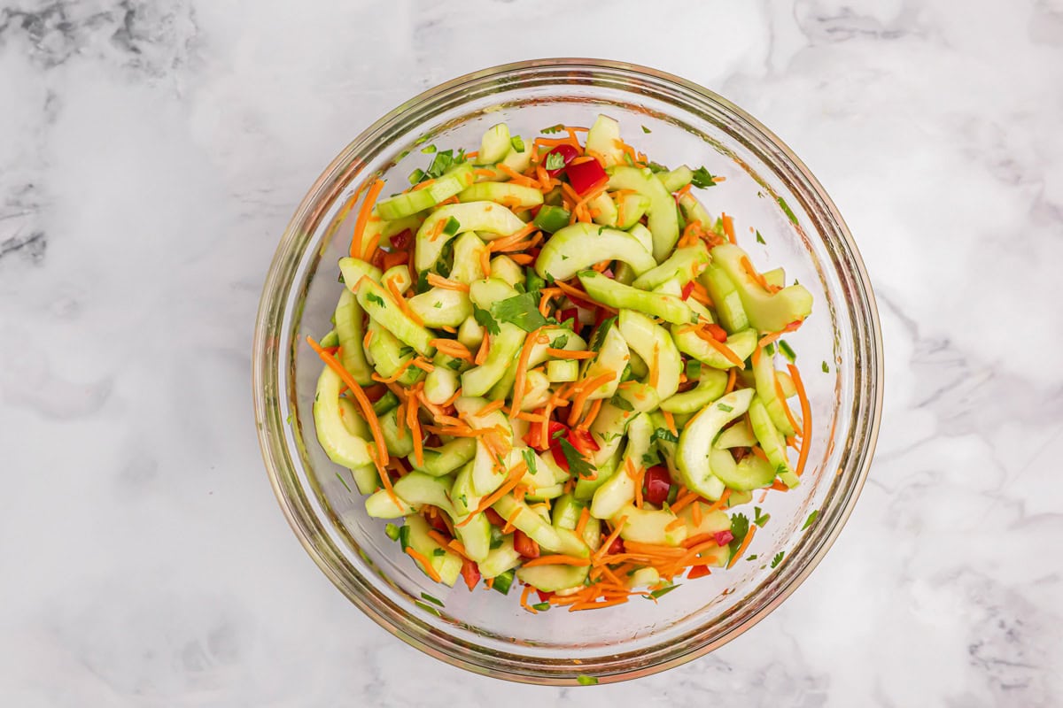 Lightly dressed chopped veggies in a glass bowl.