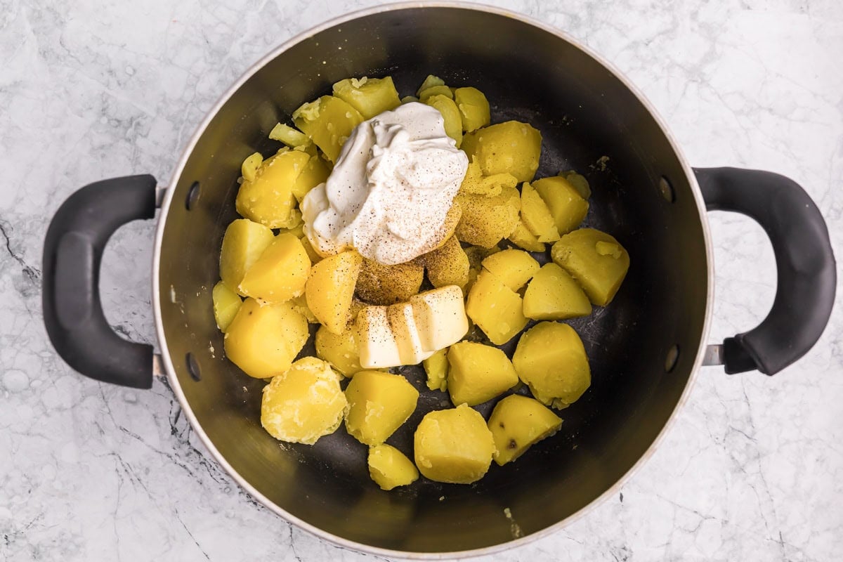 Golden potatoes and ingredients for baked mashed potatoes in pot.