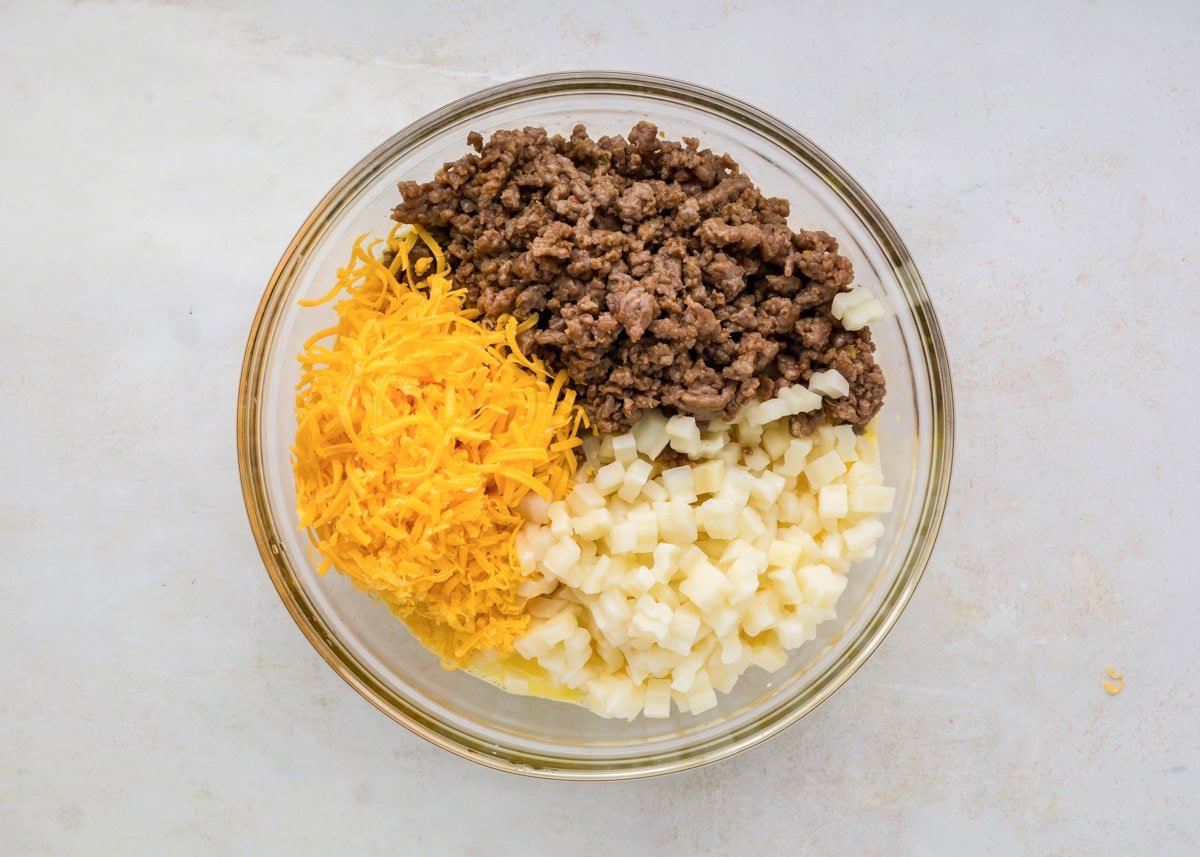 Potatoes, sausage, eggs and cheese in glass bowl.