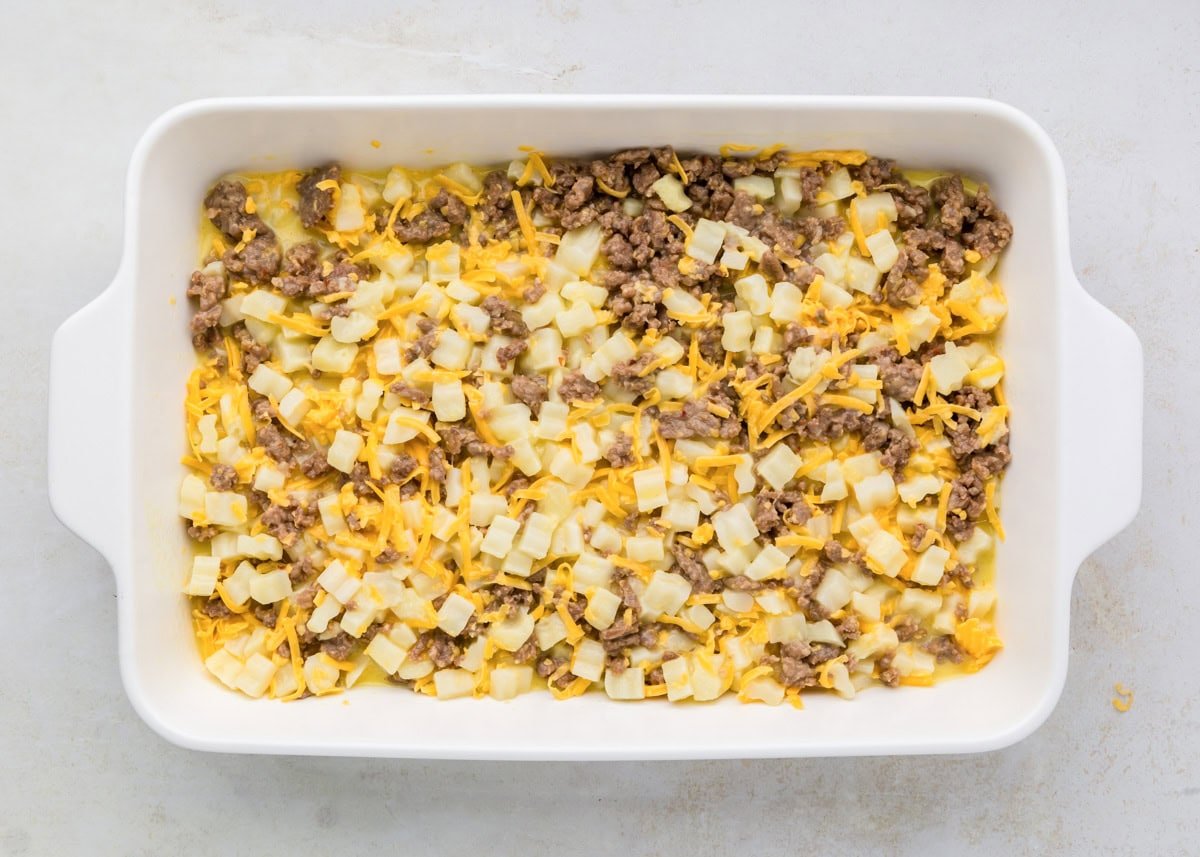 Breakfast potato casserole ingredients poured into baking dish.