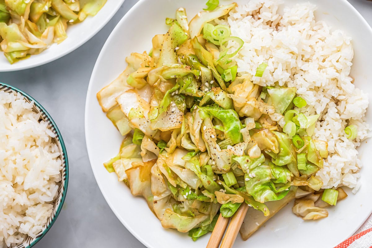 Top view of a plate of stir fry cabbage with cooked white rice.