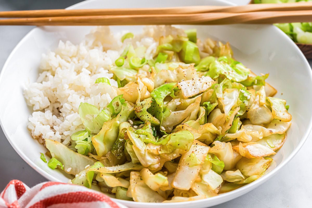 A white bowl of cabbage stir fry and rice.