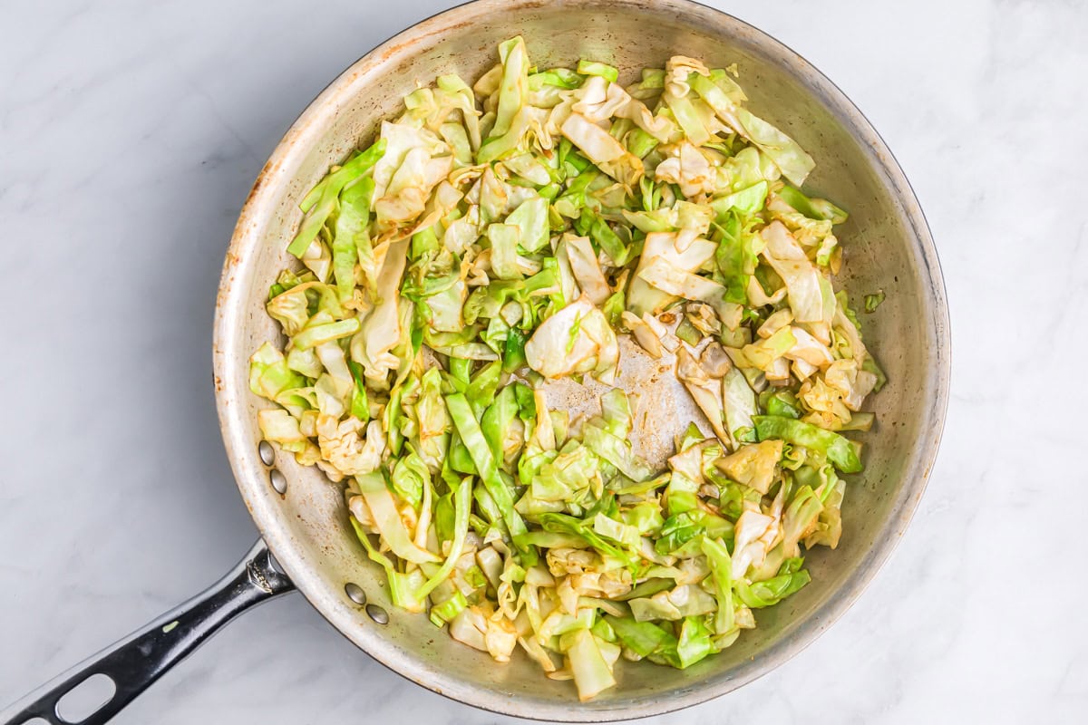 Sautéing seasoned cabbage in a pan.