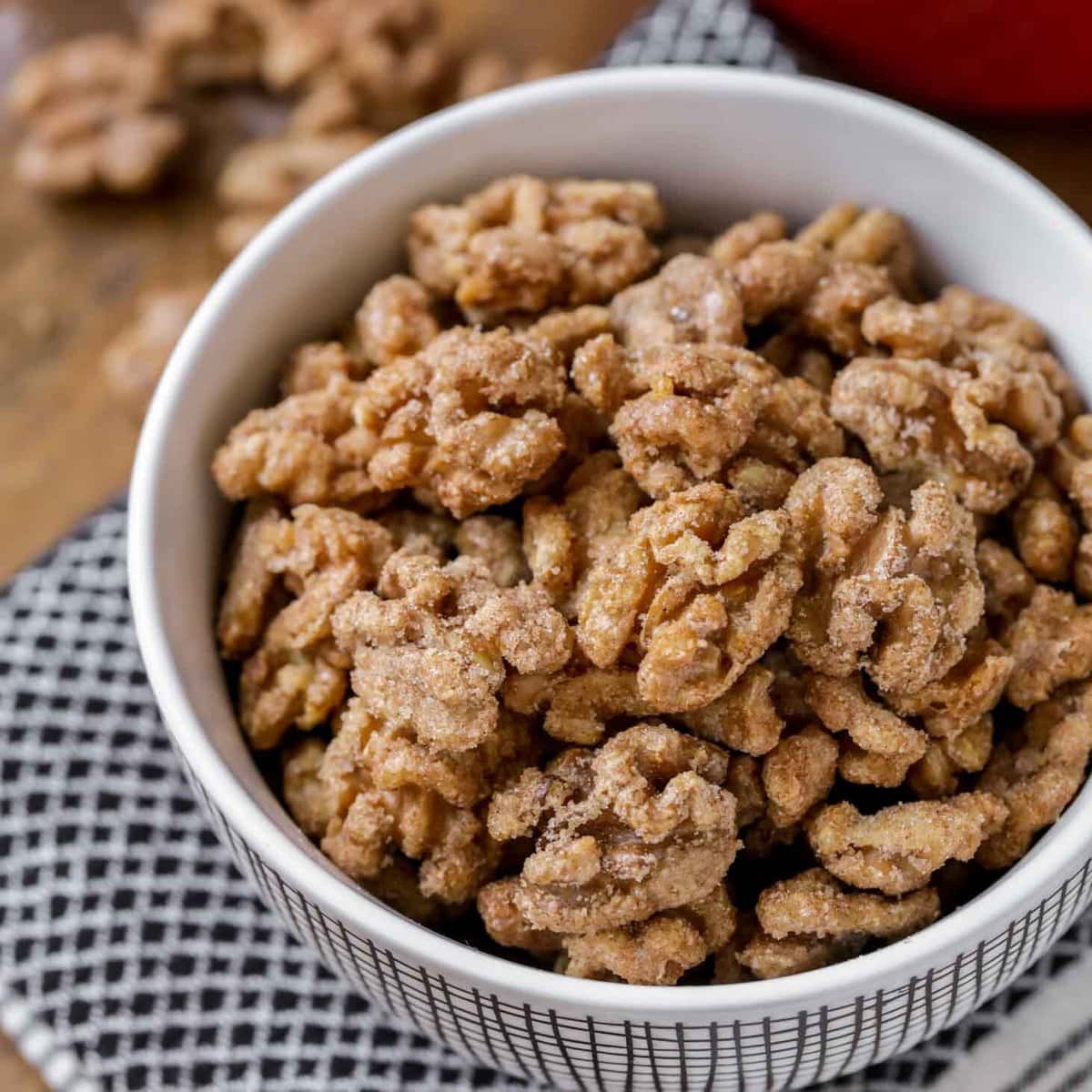 Close up image of homemade candied walnuts in white bowl.