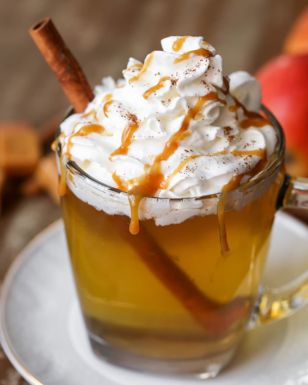 Caramel Apple cider drink topped with whipped cream and caramel drizzle.