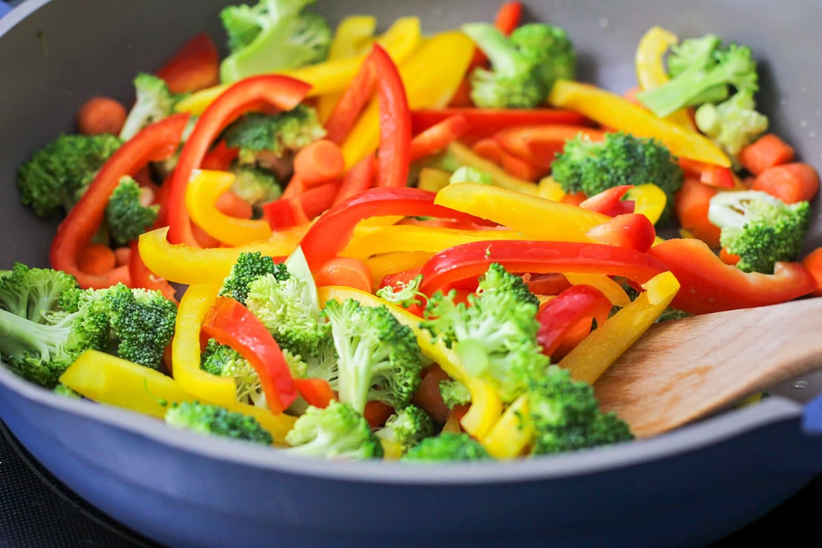 Chopped broccoli and bell peppers in a skillet.