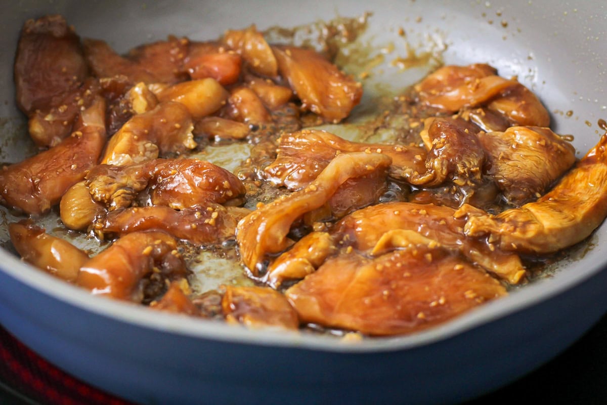 Chicken cooking in a skillet on the stove.