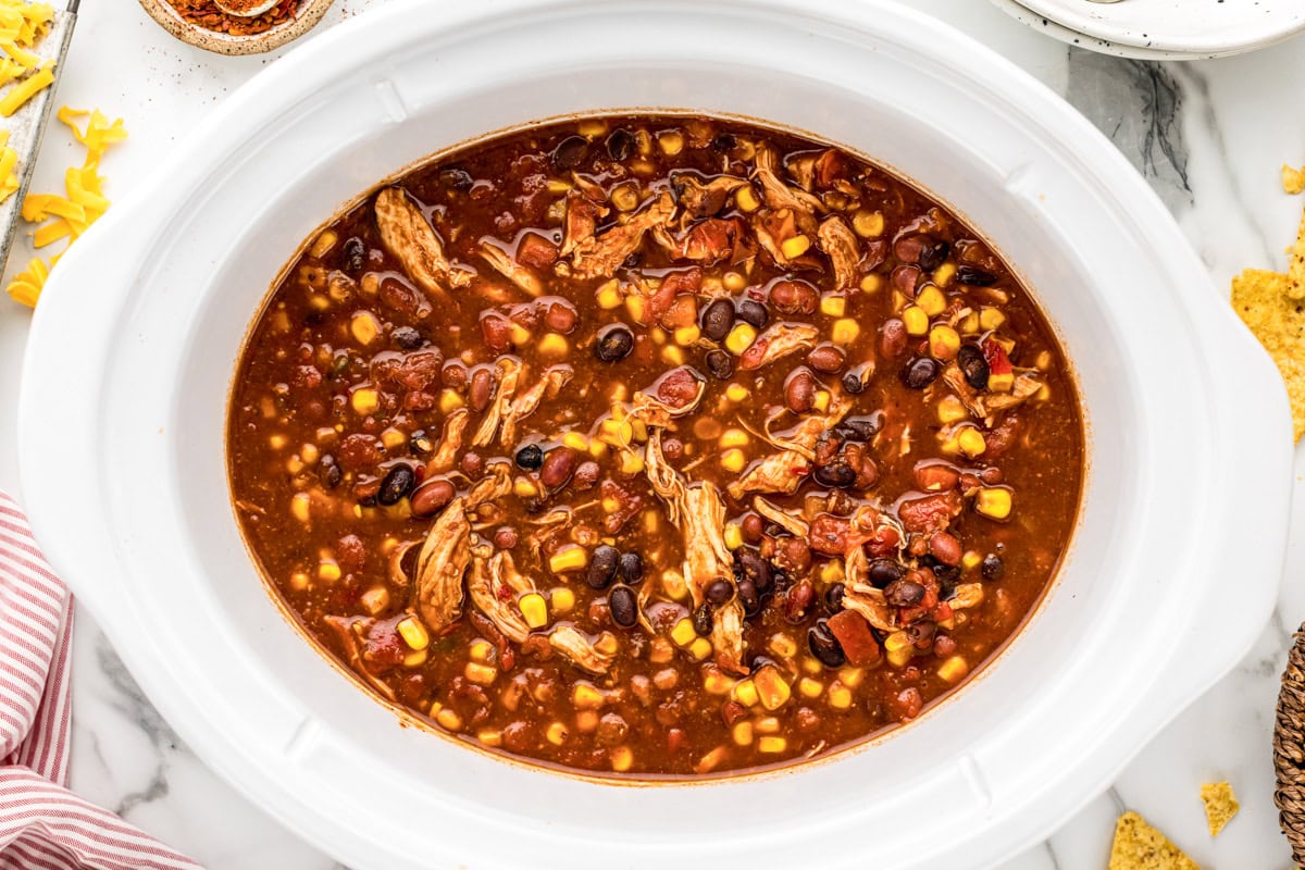 Chicken taco soup ingredients mixed together in slow cooker.