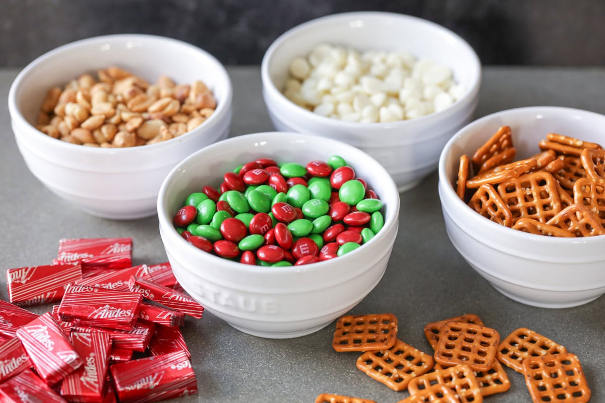 Ingredients for Christmas trail mix recipe in bowls on counter.