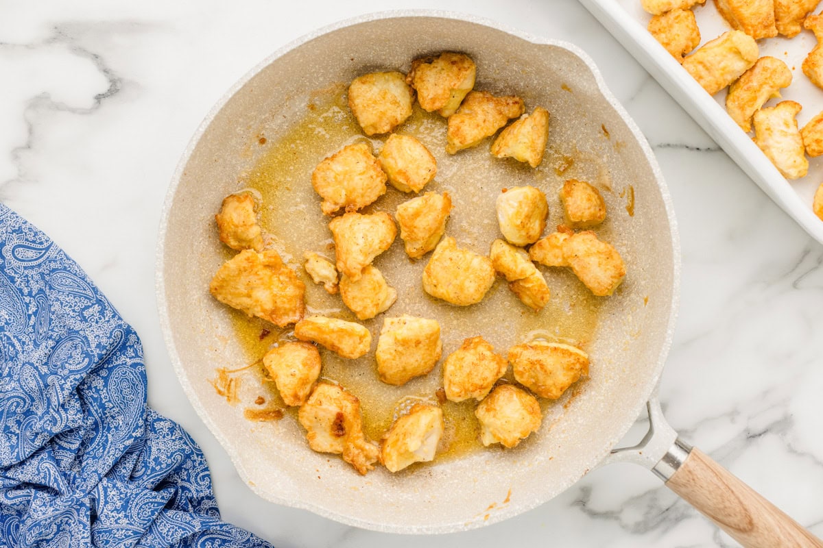 Browned chicken cubes in a skillet.