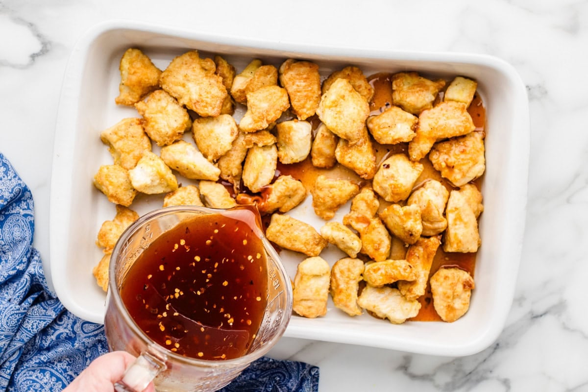 Pouring the sauce over the browned chicken cubes.