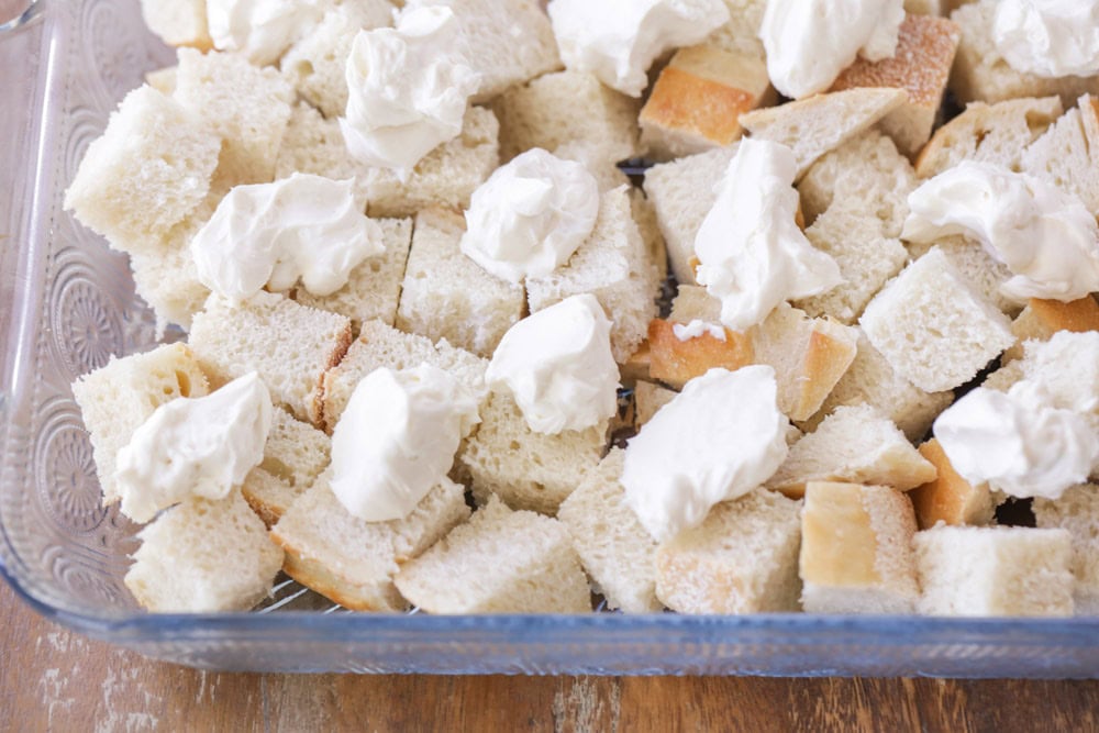 Sourdough cubes and chunks of cream cheese in casserole dish.