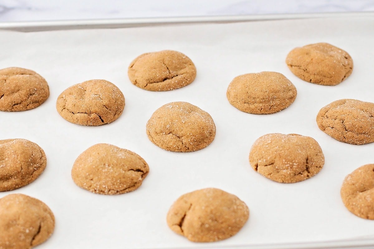 Super soft gingerdoodle cookies are perfectly spiced and coated in a cinnamon sugar mixture for two tasty cookies in one! Baked gingerdoodle cookies on a lined baking sheet.
