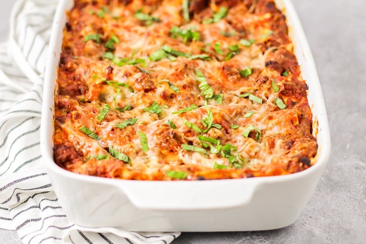 Baked lasagna in a white casserole dish.