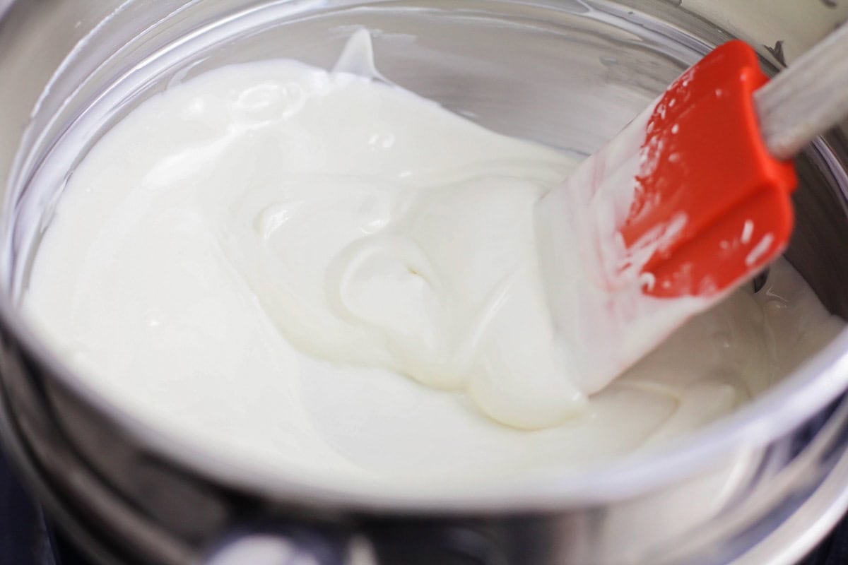 Melting white chocolate in a pan with a red spatula.