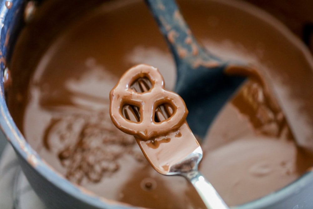 A pretzel dipped in chocolate with a fork.